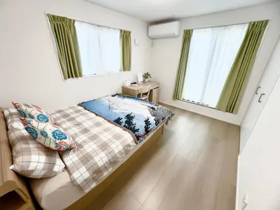 a small bedroom with a bed and two windows at Hao Bros Home Gemini in Tokyo