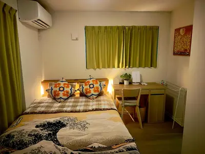 a bedroom with a bed with a desk and green curtains at Hao Bros Home Gemini in Tokyo
