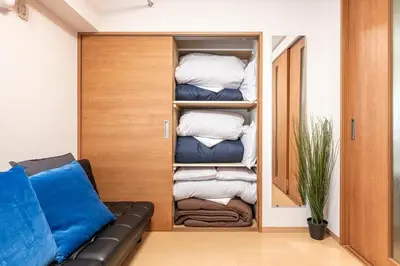 a room with a couch and a closet with towels at \u6771\u4eac\u99c5\u3084\u79cb\u8449\u539f\u99c5\u304b\u3089\u96fb\u8eca\u3067\u30a2\u30af\u30bb\u30b9\u826f\u597d in Tokyo