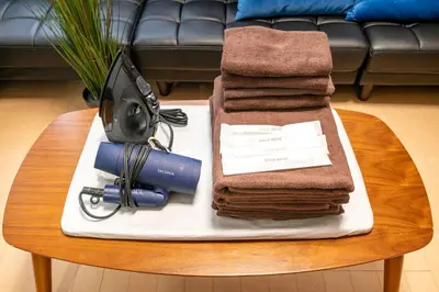 a table with a pile of towels and a hair dryer at \u6771\u4eac\u99c5\u3084\u79cb\u8449\u539f\u99c5\u304b\u3089\u96fb\u8eca\u3067\u30a2\u30af\u30bb\u30b9\u826f\u597d in Tokyo