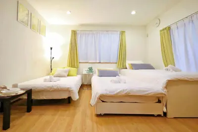 a room with three beds and a table and a window at \u65b0\u5bbf\u521d\u53f0\u30a2\u30d1\u30fc\u30c8 in Tokyo
