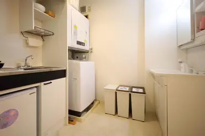 a small kitchen with white cabinets and a refrigerator at \u65b0\u5bbf\u521d\u53f0\u30a2\u30d1\u30fc\u30c8 in Tokyo