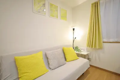 a white couch with yellow pillows in a room at \u65b0\u5bbf\u521d\u53f0\u30a2\u30d1\u30fc\u30c8 in Tokyo