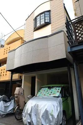 a small green car parked in front of a building at \u65b0\u5bbf\u521d\u53f0\u30a2\u30d1\u30fc\u30c8 in Tokyo