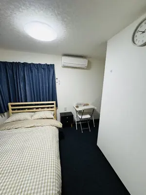 a room with two beds and a table and a clock at Toho so Inn in Tokyo