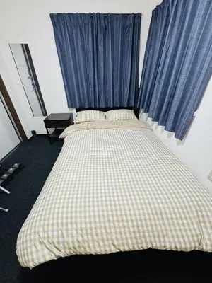 a bed with a checkered blanket in a bedroom at Toho so Inn in Tokyo