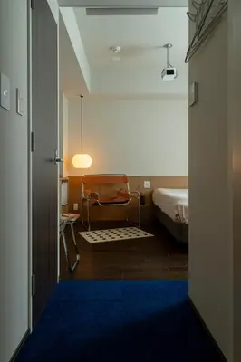 a view of a bedroom with a bed and a blue rug at etoe Hotel Shinjuku in Tokyo