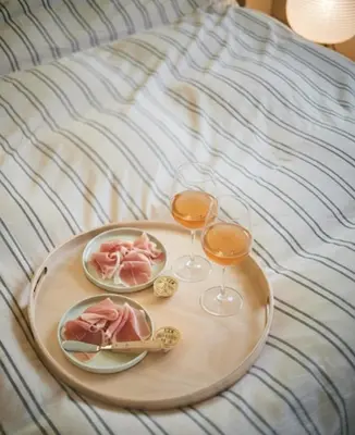 a tray of food and two glasses of wine on a bed at etoe Hotel Shinjuku in Tokyo
