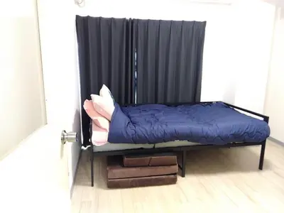 a bed in a room with a black curtain at SunandMoon\u30db\u30c6\u30eb401 in Tokyo