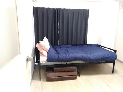 a bed in a room with a black curtain at SunandMoon\u30db\u30c6\u30eb401 in Tokyo