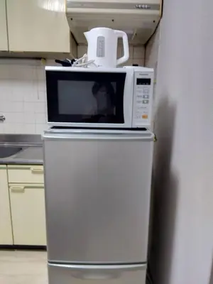 a microwave on top of a refrigerator in a kitchen at SunandMoon\u30db\u30c6\u30eb401 in Tokyo