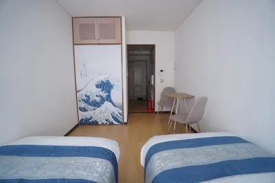 a room with two beds and a painting of a wave at \u3055\u304f\u3089\u30b3\u30f3\u30d5\u30a9\u30fc\u30c8 in Tokyo