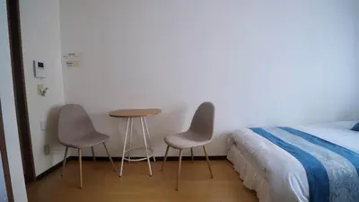 a bedroom with two chairs and a table next to a bed at \u3055\u304f\u3089\u30b3\u30f3\u30d5\u30a9\u30fc\u30c8 in Tokyo