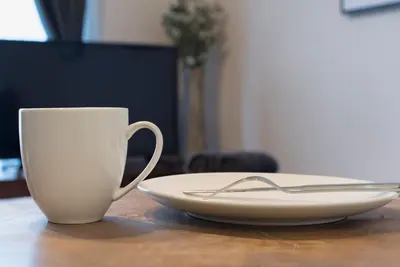 a white coffee cup and a plate on a table at Villa Wisteria Kitazawa -apartment hotel- in Tokyo