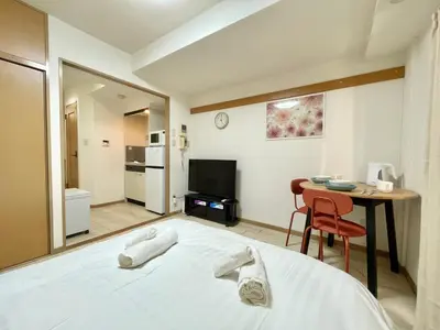 a bedroom with a bed and a table and a kitchen at YMK Oshiage 3A in Tokyo