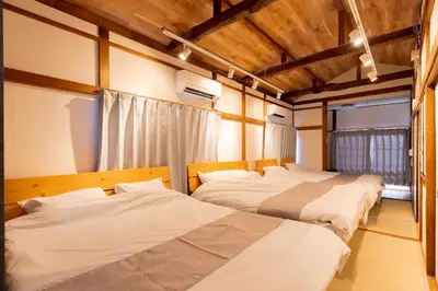 three beds in a room with wooden ceilings at Renovated House Crossroads Katsushika in Tokyo