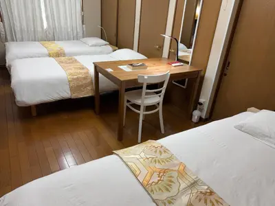 a room with three beds and a wooden table with a chair at 西巣鴨 Cozy for 4-12guests 3BR House-3Showers &3Toilets in Tokyo