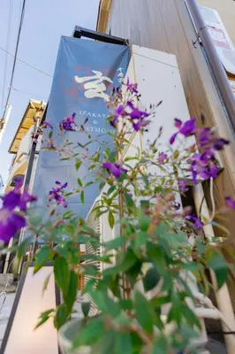 a plant with purple flowers sitting next to a sign at \u5343\u5bff\u5bbf \u7384 in Tokyo