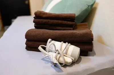 a pile of towels and a hair dryer on a bed at 4min Shinjuku by sub Cozy Mini Room in Tokyo