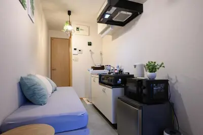 a small kitchen with a couch and a microwave at 4min Shinjuku by sub Cozy Mini Room in Tokyo