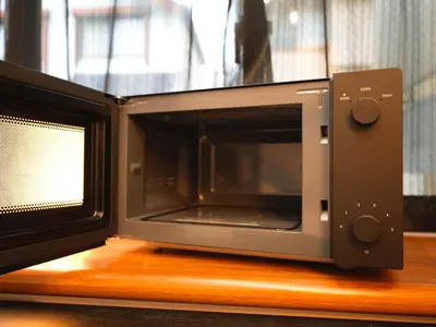 a microwave sitting on top of a wooden table at The Nest Koenji Cozy Stay near Station Easy Access to Shinjuku in Tokyo