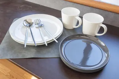 a table with two plates and utensils and two cups at The Nest Koenji Cozy Stay near Station Easy Access to Shinjuku in Tokyo