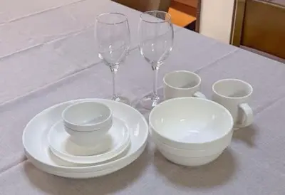 a table with two wine glasses and white plates at \u30a8\u30de\u30fc\u30ec\u65b0\u5bbf401\u53f7\u5ba4 in Tokyo