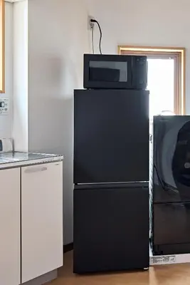 a microwave sitting on top of a black refrigerator at Pufuka\u6771\u5411\u5cf6\u5317\u516c\u5712 in Tokyo