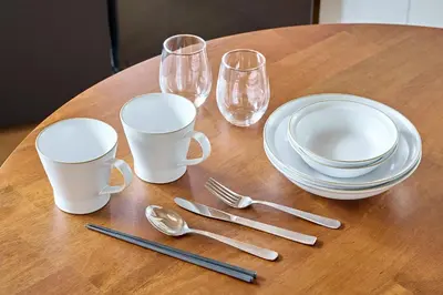 a wooden table with plates and glasses and silverware at Pufuka\u6771\u5411\u5cf6\u5317\u516c\u5712 in Tokyo