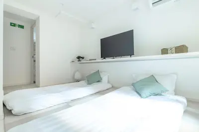 two beds in a room with a tv on the wall at Downtown Mix in Tokyo