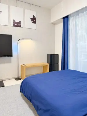 a bedroom with a blue bed and a television at Triphome Shinjuku East in Tokyo