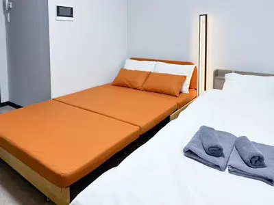 two beds in a room with orange sheets and towels at Triphome Shinjuku East in Tokyo