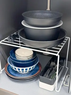 a stack of plates and pans on a shelf in a kitchen at Triphome Shinjuku East in Tokyo