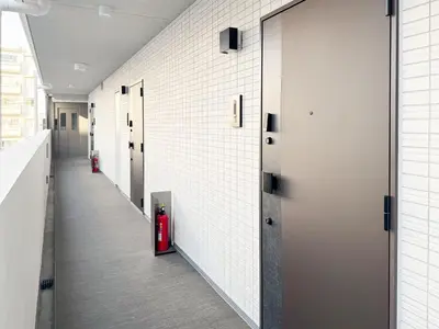 a hallway with white walls and a fire extinguisher at Triphome Shinjuku East 4F in Tokyo