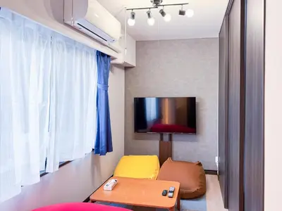 a living room with a couch and a tv on a wall at Triphome Shinjuku East 4F in Tokyo