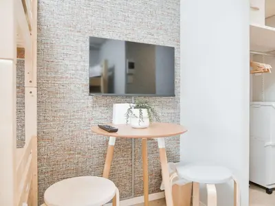 a small table in a room with a tv on a brick wall at Triphome Nakano 2025 Bunk bed in Tokyo
