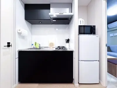 a small kitchen with a black and white refrigerator at Triphome Nakano 2025 Penthouse in Tokyo
