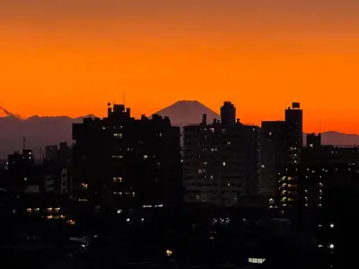 a city skyline at sunset with a mountain in the background at Triphome Nakano 2025 Penthouse in Tokyo