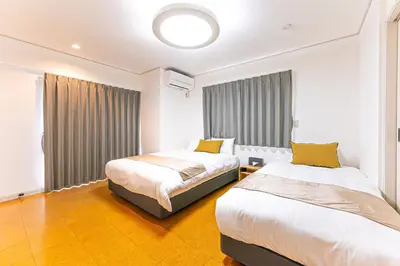 two beds in a hotel room with yellow pillows at Poka villa aoyama - Vacation STAY 19050 in Tokyo