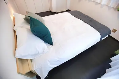 a large bed with white sheets and green pillows at Miraisya Hikifune in Tokyo