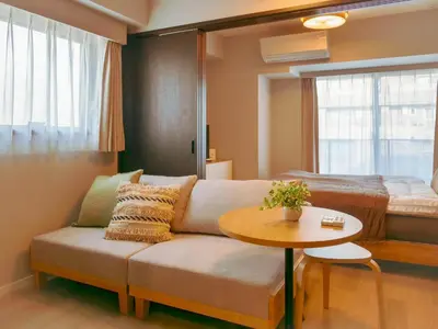 a living room with a couch and a table and a bed at Triphome Nakano 2025 Cozy in Tokyo