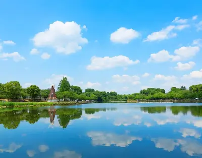 a lake with a windmill and clouds in the sky at \u685c\u306e\u5bbf in Tokyo