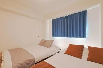 a bedroom with two beds and a window with blue curtains at V Close to Kikukawa sta 14 min to Akihabara in Tokyo