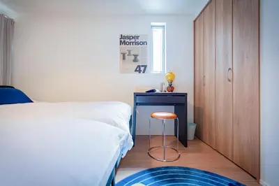 a bedroom with a bed and a stool next to a desk at Ikebukuro Japandi Villa in Tokyo