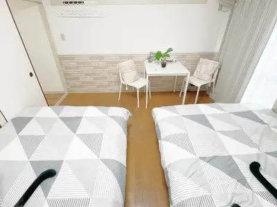 two beds in a room with a table and chairs at Takadanobaba RedH in Tokyo