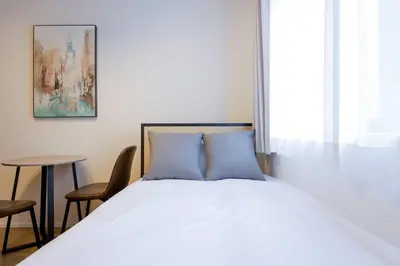 a bedroom with a bed with blue pillows and a table at \u30ea\u30d0\u30c6\u30a3 in Tokyo