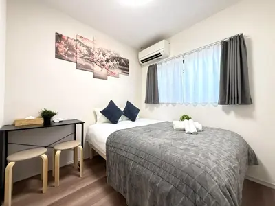 a bedroom with two beds and a desk and a window at Ikebukuro Area 2 Units 2122 KamiikeApartment in Tokyo