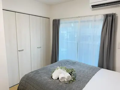 a bedroom with a bed with two towels and a window at Ikebukuro Area 2 Units 2122 KamiikeApartment in Tokyo