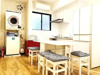 a kitchen with white cabinets and a counter with stools at Maison Okuasakusa in Tokyo
