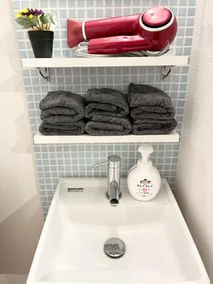a bathroom with a sink and towels on shelves at Yotsugi Hotel Asakusa Skytree in Tokyo